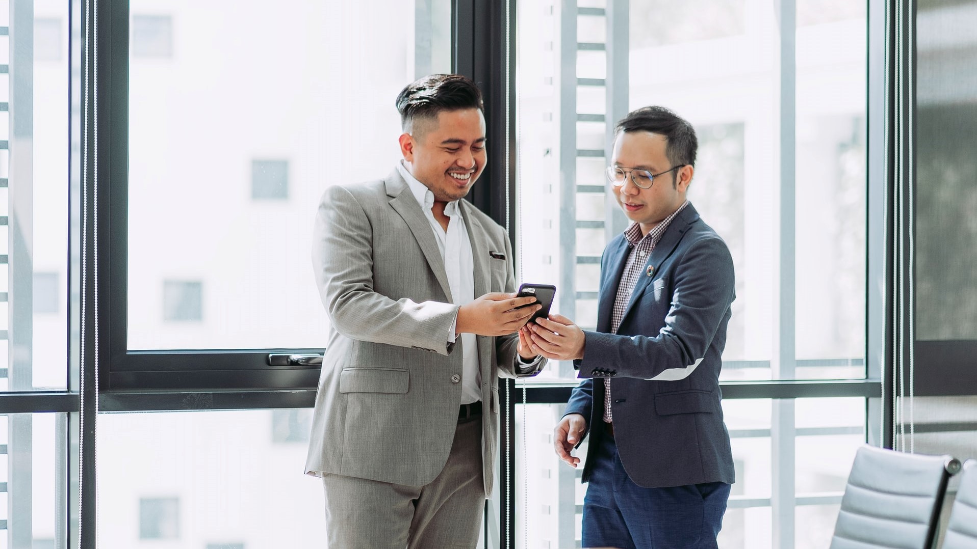 businessman sharing something on his phone to demonstrate value to another businessman